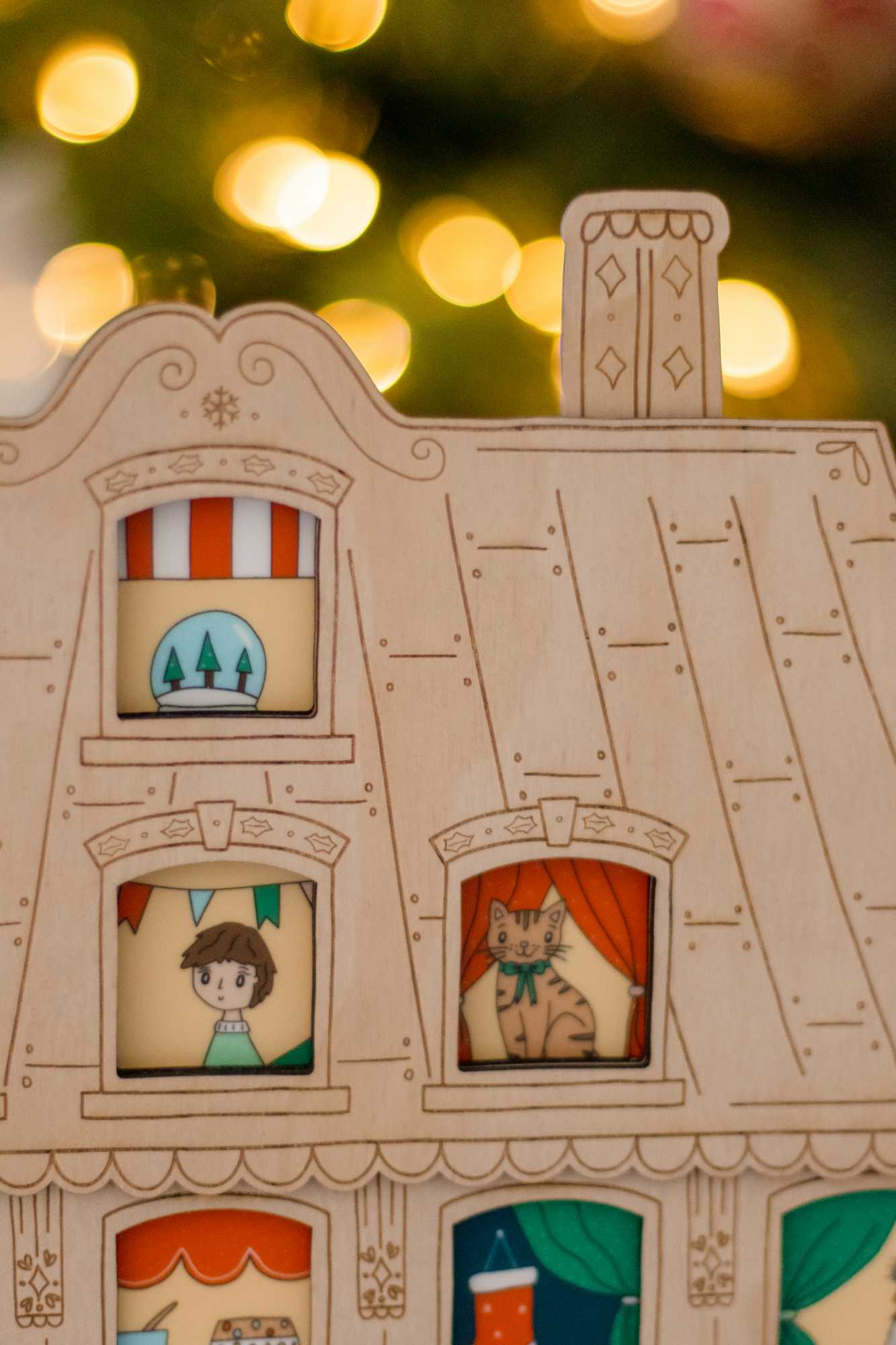 A close up view of the festive apartment advent calendar showing the windows with a little boy and a cute cat looking out