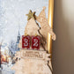 Wooden Christmas tree advent calendar with snowflake design, against a blurred winter scene background.
