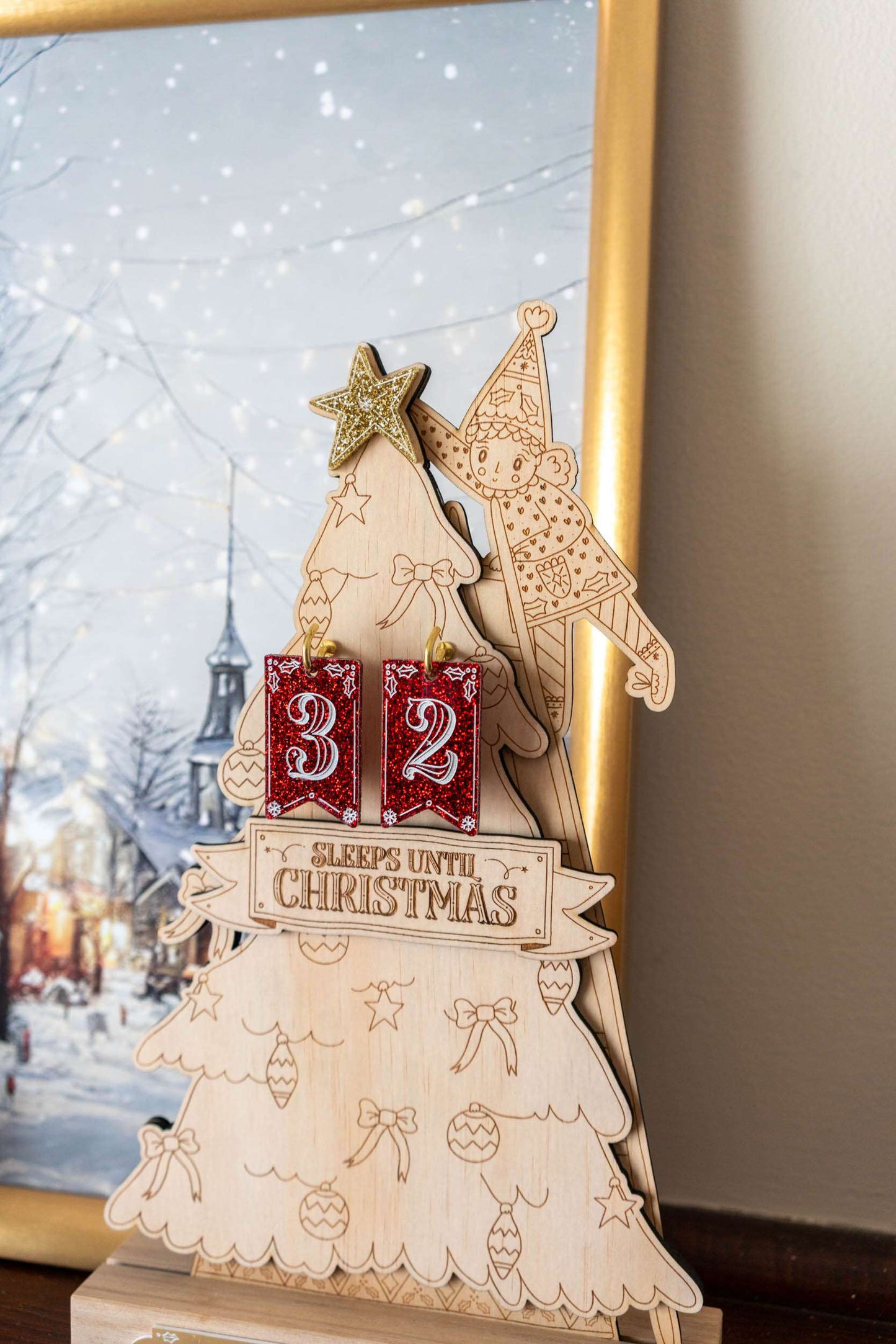 Wooden Christmas tree advent calendar with snowflake design, against a blurred winter scene background.