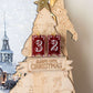 Wooden Christmas countdown tree with '32 sleeps until Christmas' on a blurred snowy background
