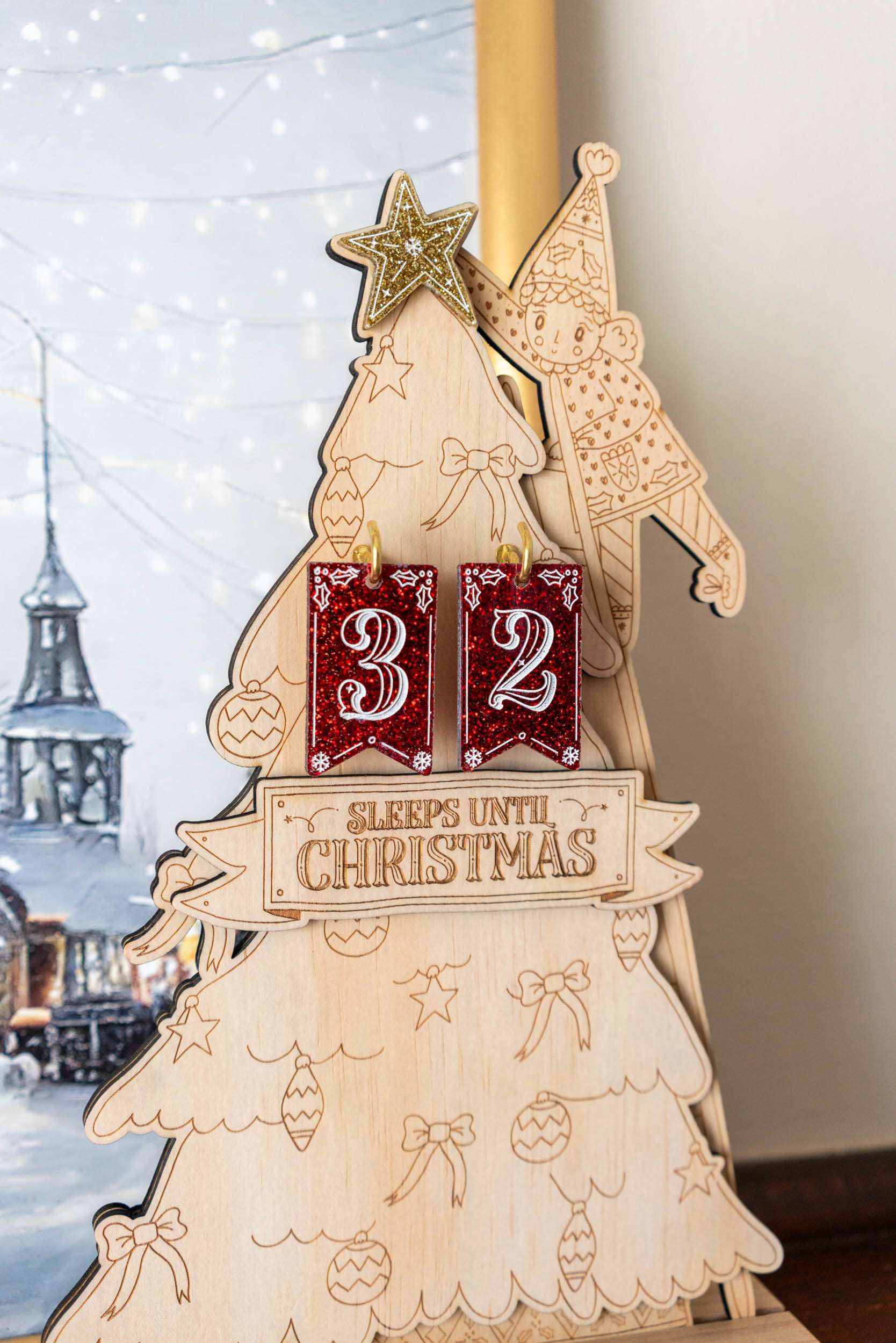 Wooden Christmas countdown tree with '32 sleeps until Christmas' on a blurred snowy background
