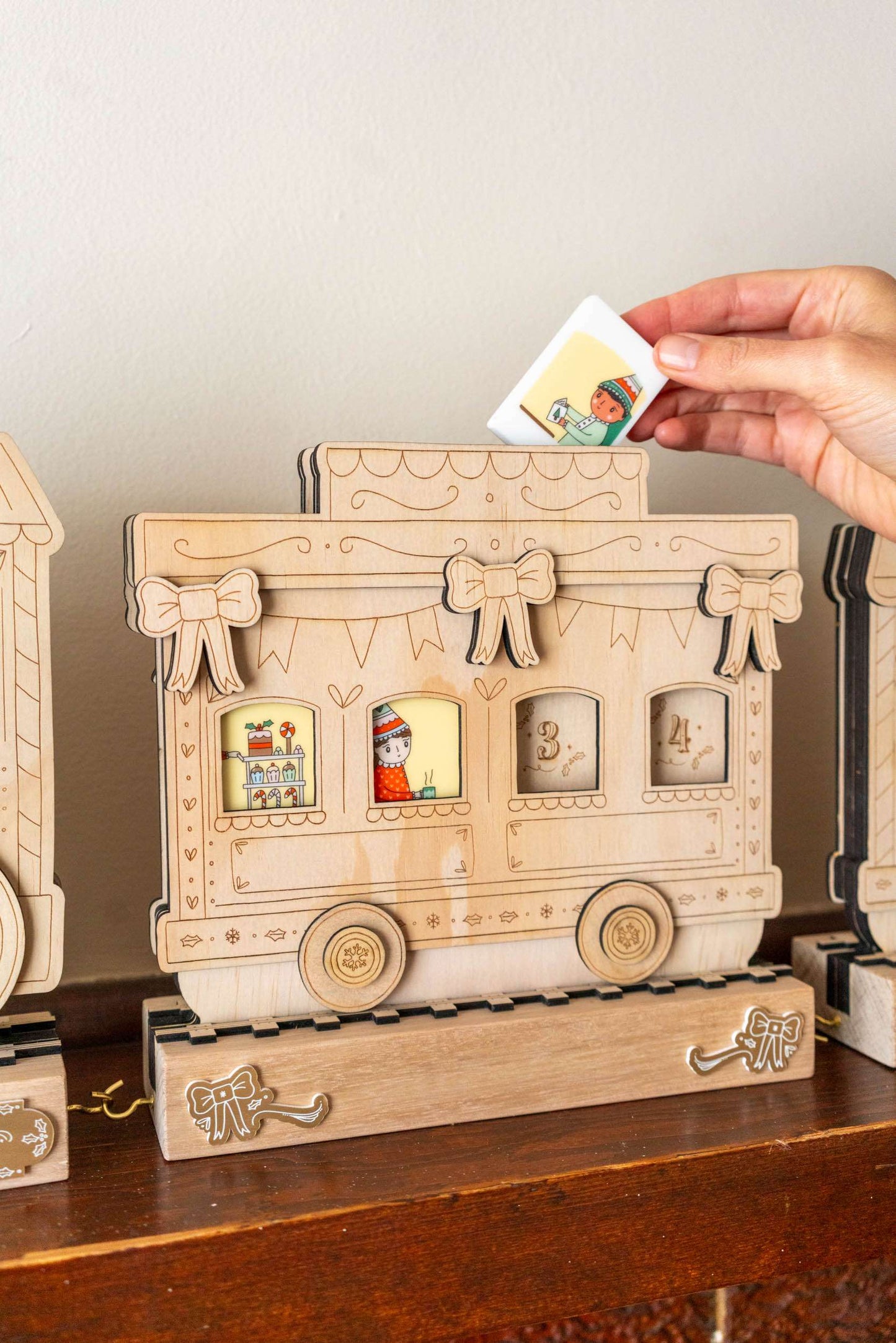 Wooden advent calendar shaped like a vintage train with decorative bows on a wooden surface.