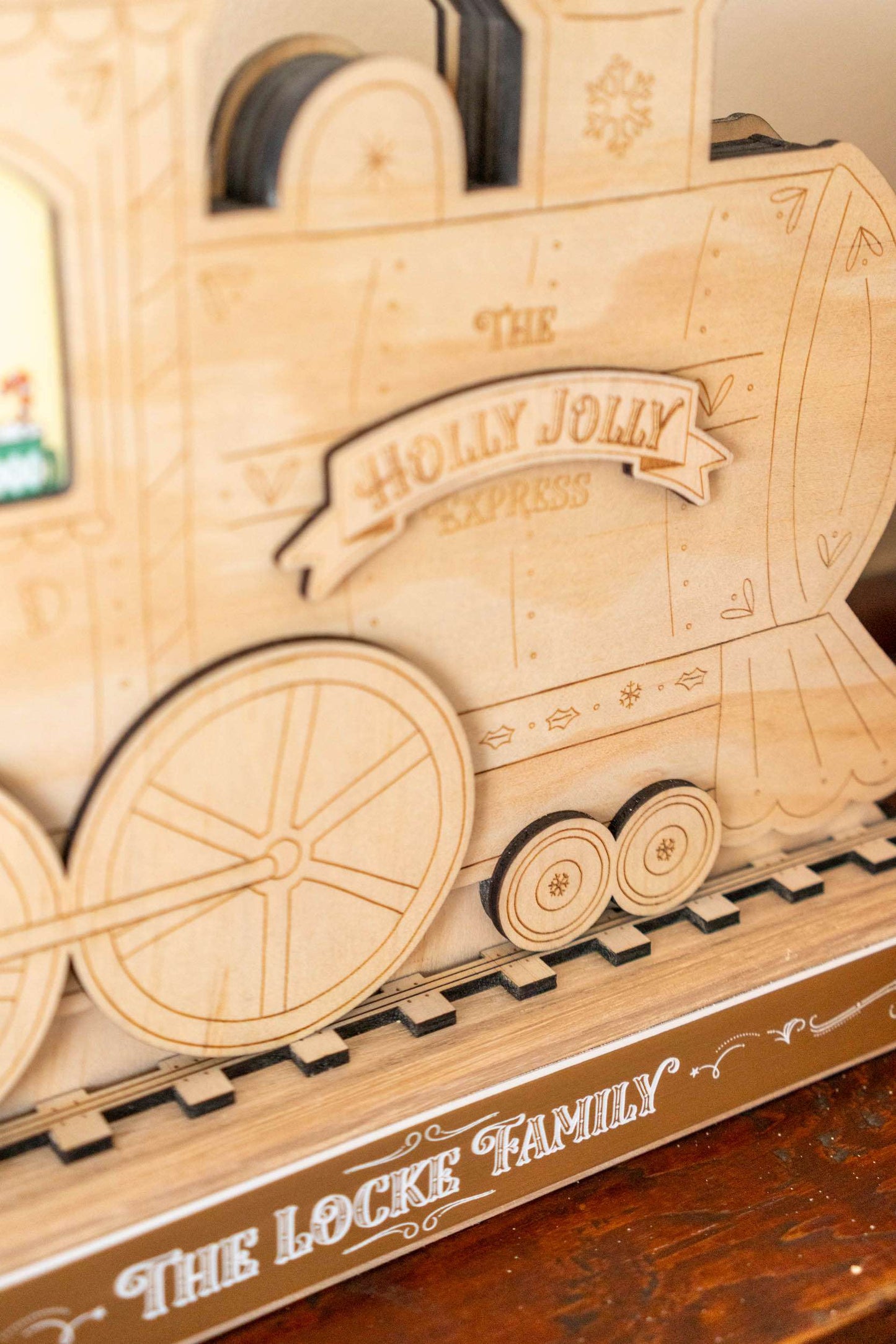 Wooden toy train model with 'The Holly Jolly Express' and 'The Locke Family' branding on a wooden surface.