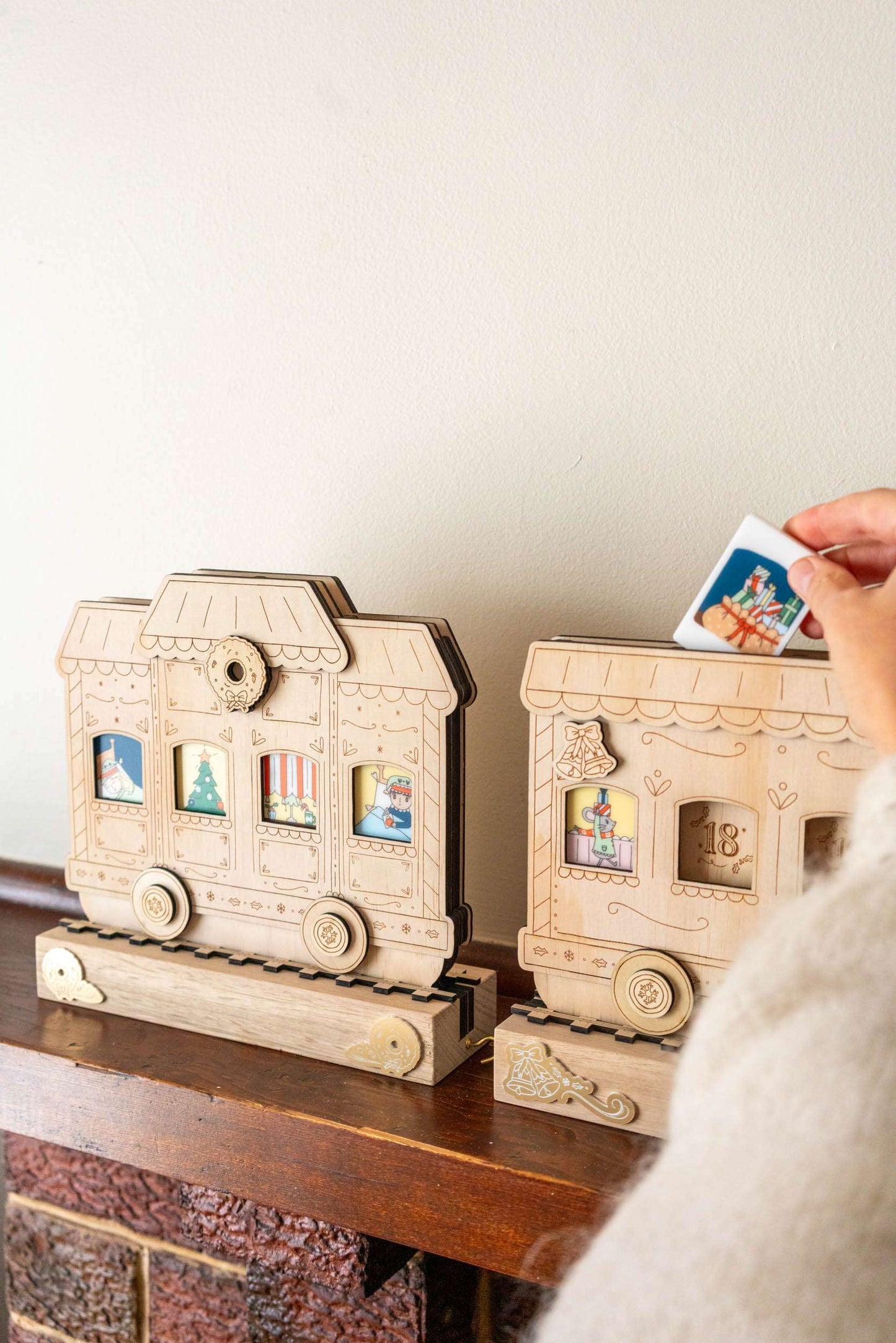 A wooden train advent calendar with a hand placing a tile in