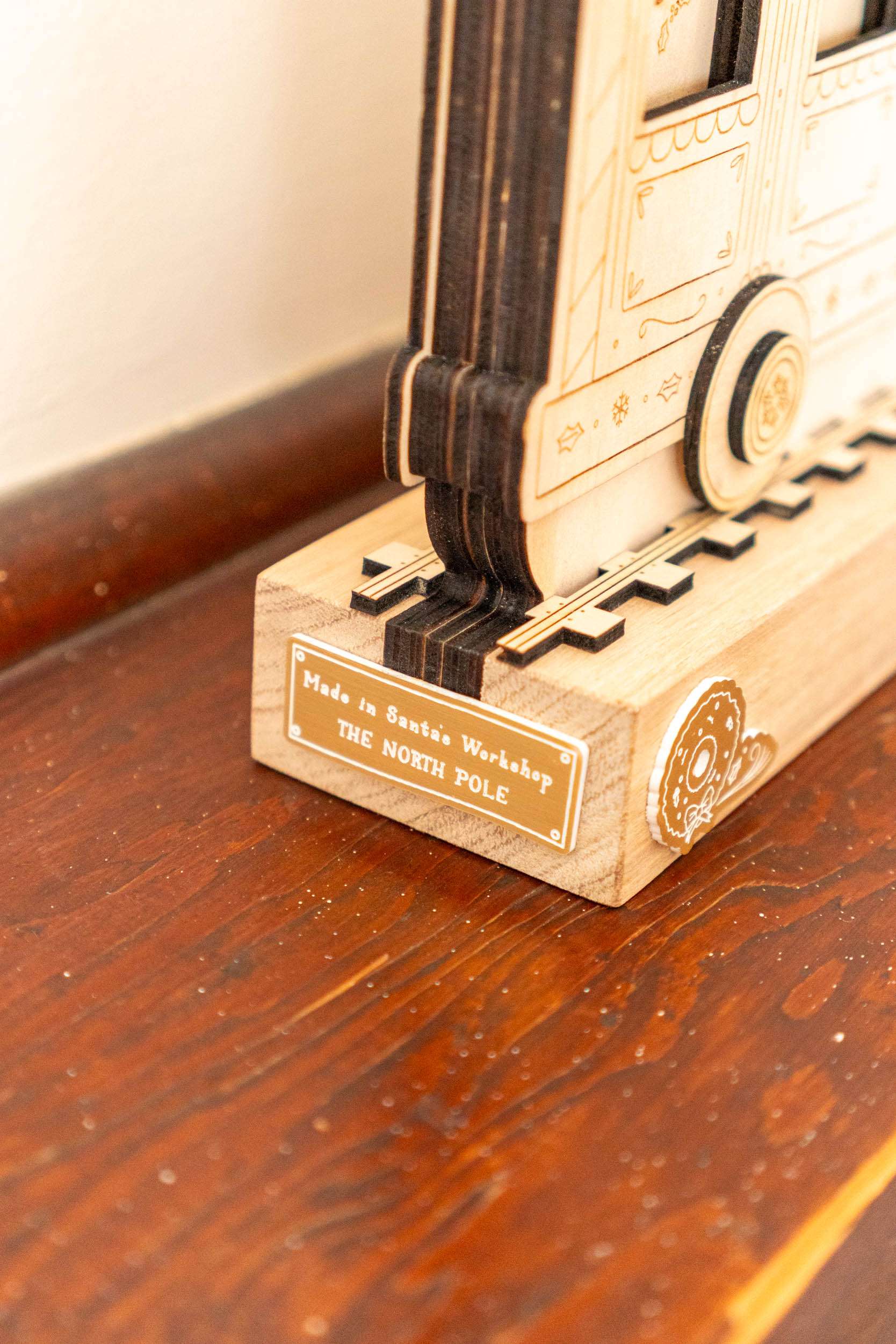 Wooden model of a train on a wooden surface with a label reading 'Made in Santa's Workshop THE NORTH POLE'.