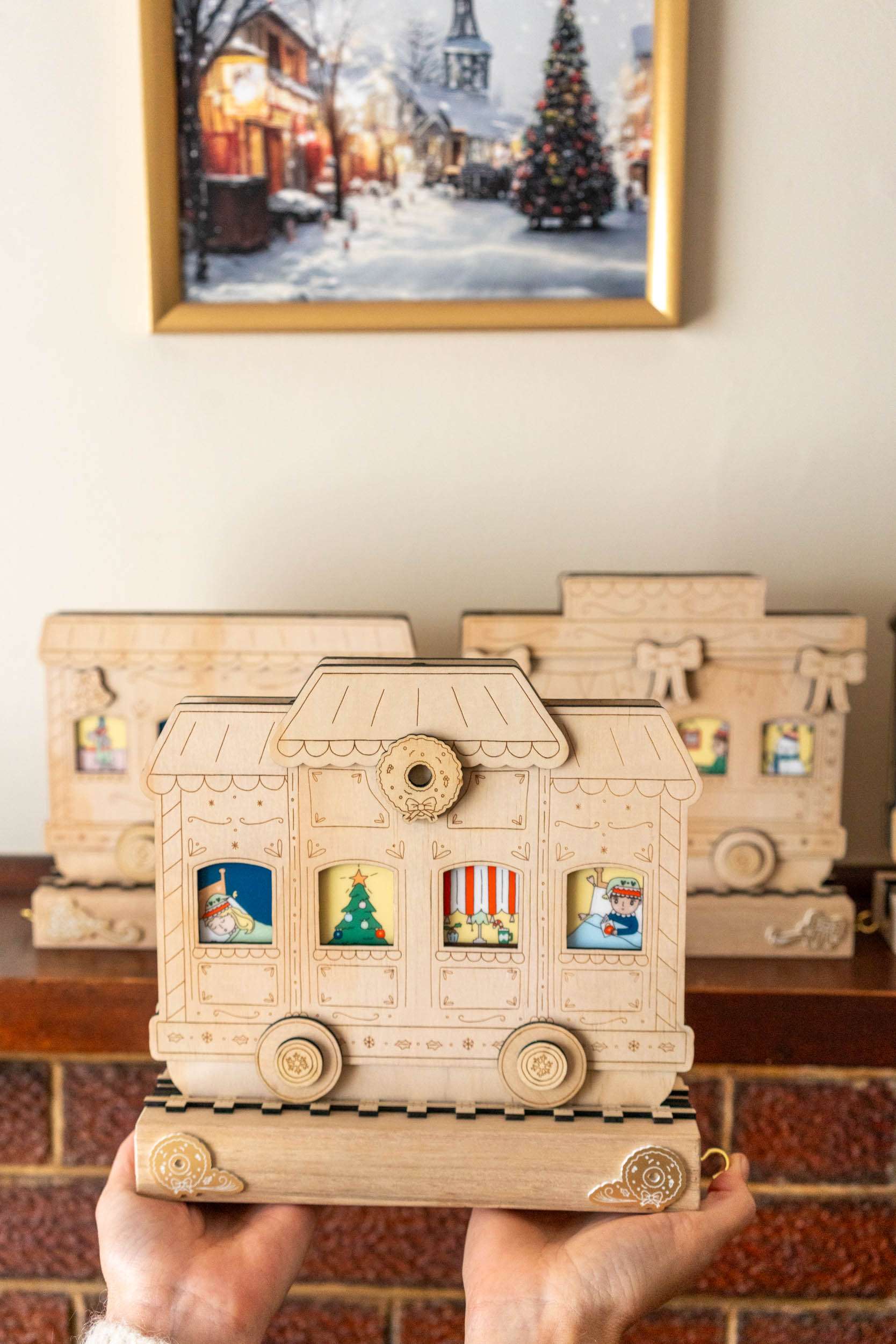 Wooden advent calendar held in front of a fireplace with Christmas decorations.